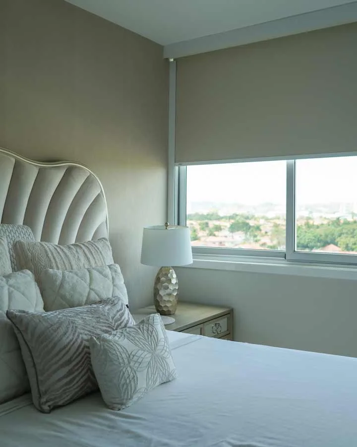 Blackout roller shade partly lowered over a bedroom window