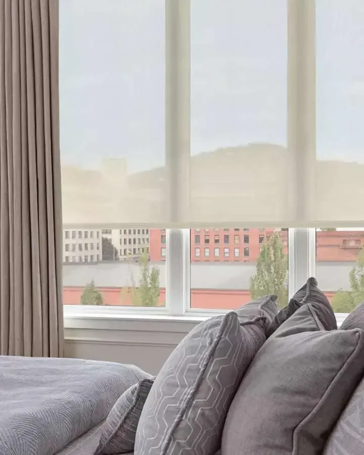 Light-filtering roller shades beside full-length drapery in a living room